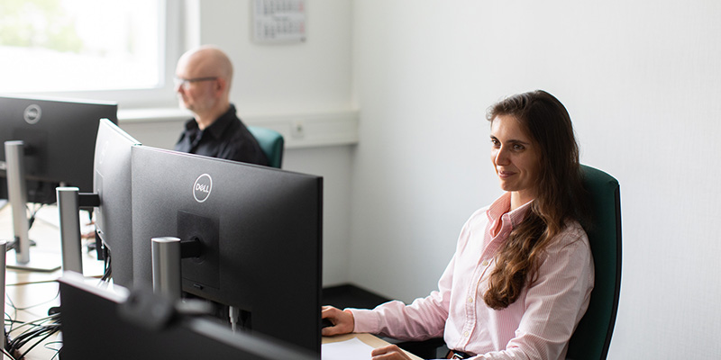 Eine Frau und ein Mann sitzen jeweils vor einem PC