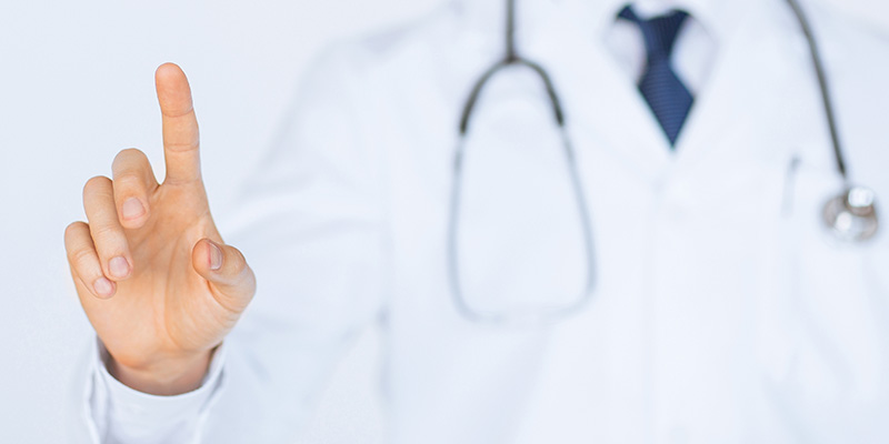 Arzt im weißen Kittel und Stethoskop zeigt auf Screen